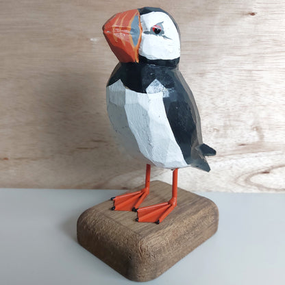 Wooden sculpture of a puffin on a wooden base with a light wood background