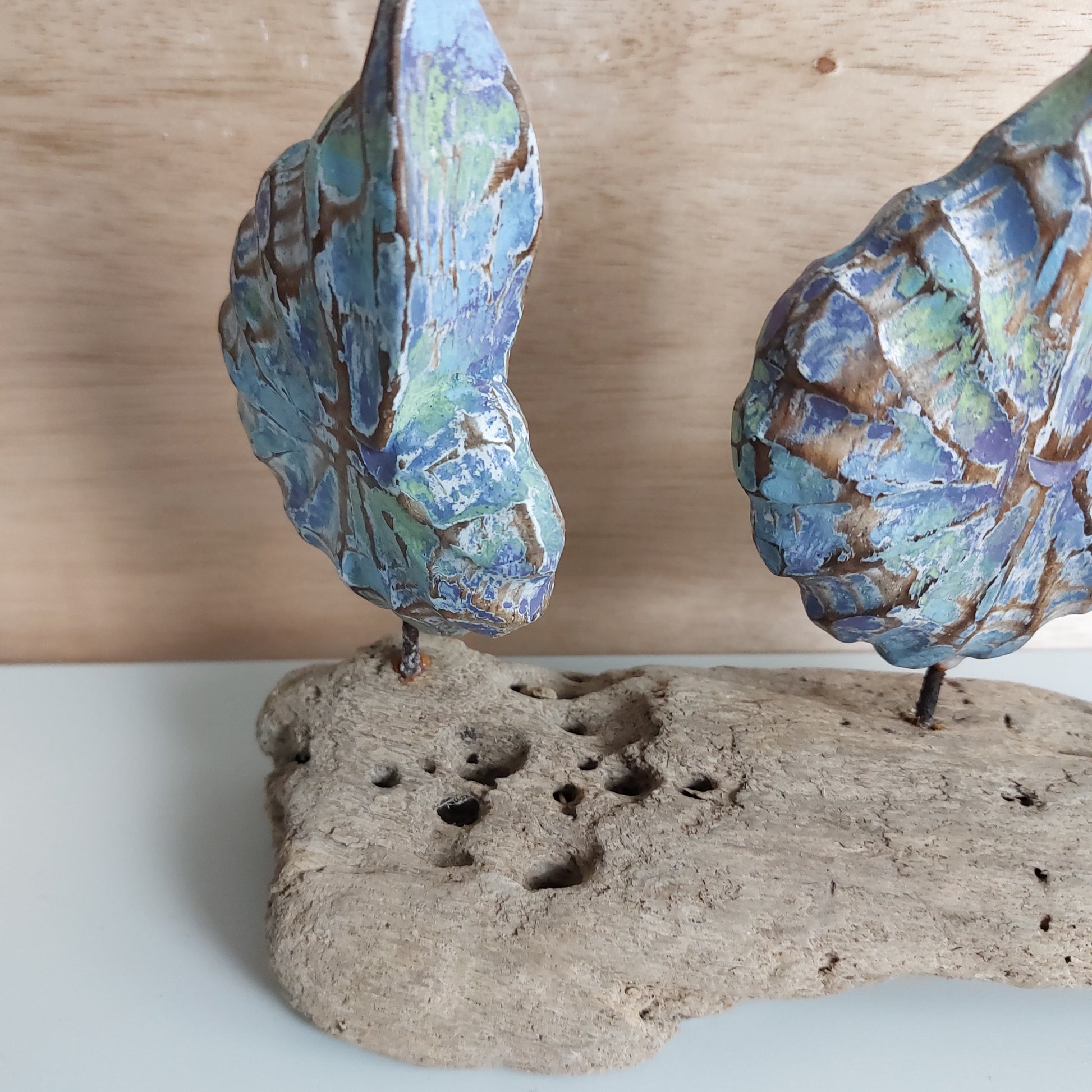Decorative hand carved and painted wooden shell sculpture with blue and green patterns on a wooden background