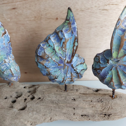 Close up of a wooden hand made shell ornament with blue and green patterns on a wooden surface.