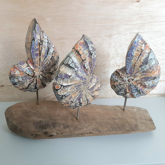 A wooden ornament of 3 shells on a wooden base with a wooden background