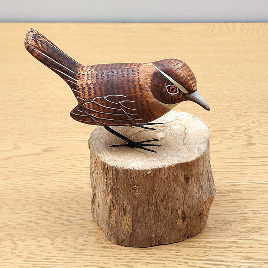 Wooden handmade carved Wren bird figurine on a wooden log base against a beige background