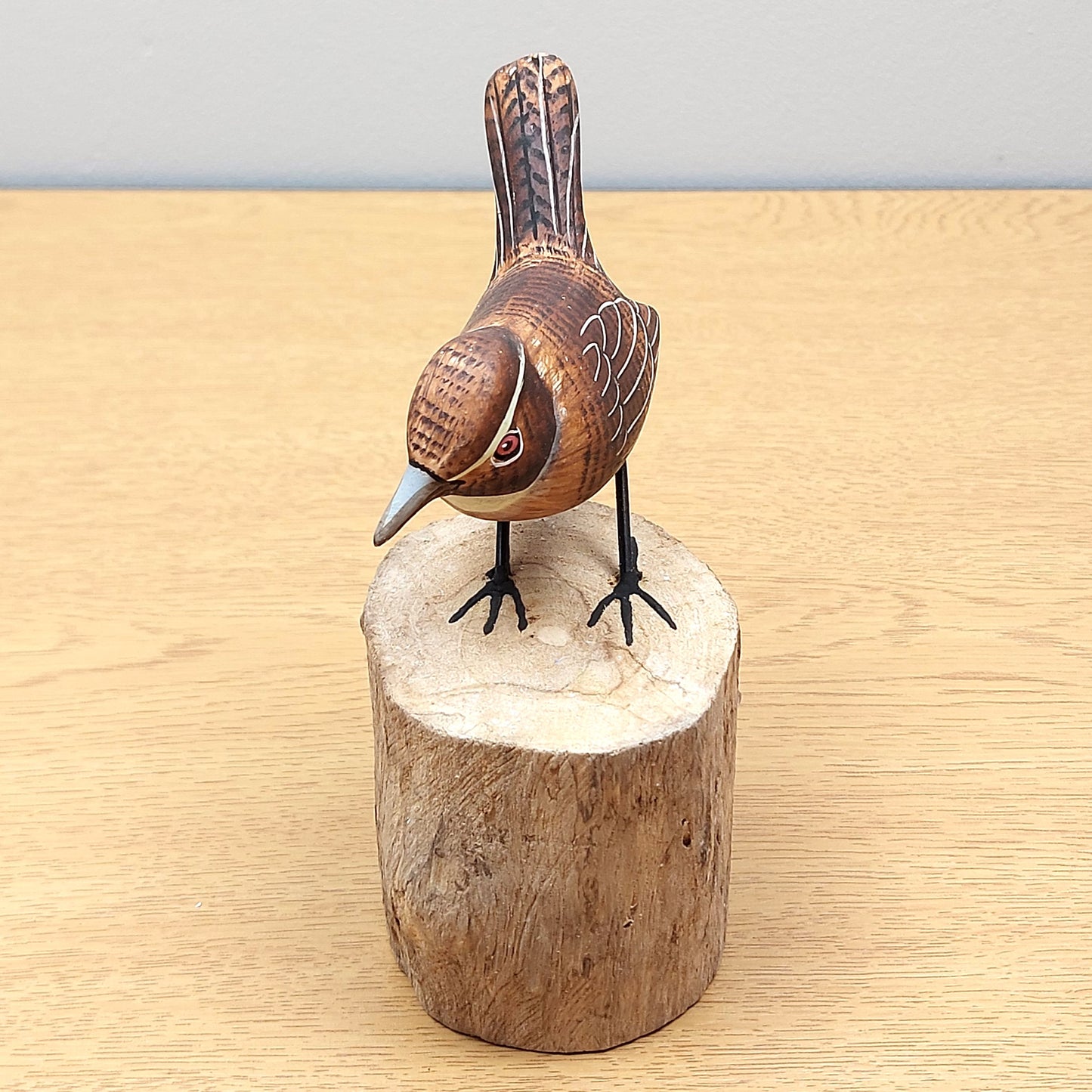Wooden Wren bird figurine on a wooden block against a light gray background
